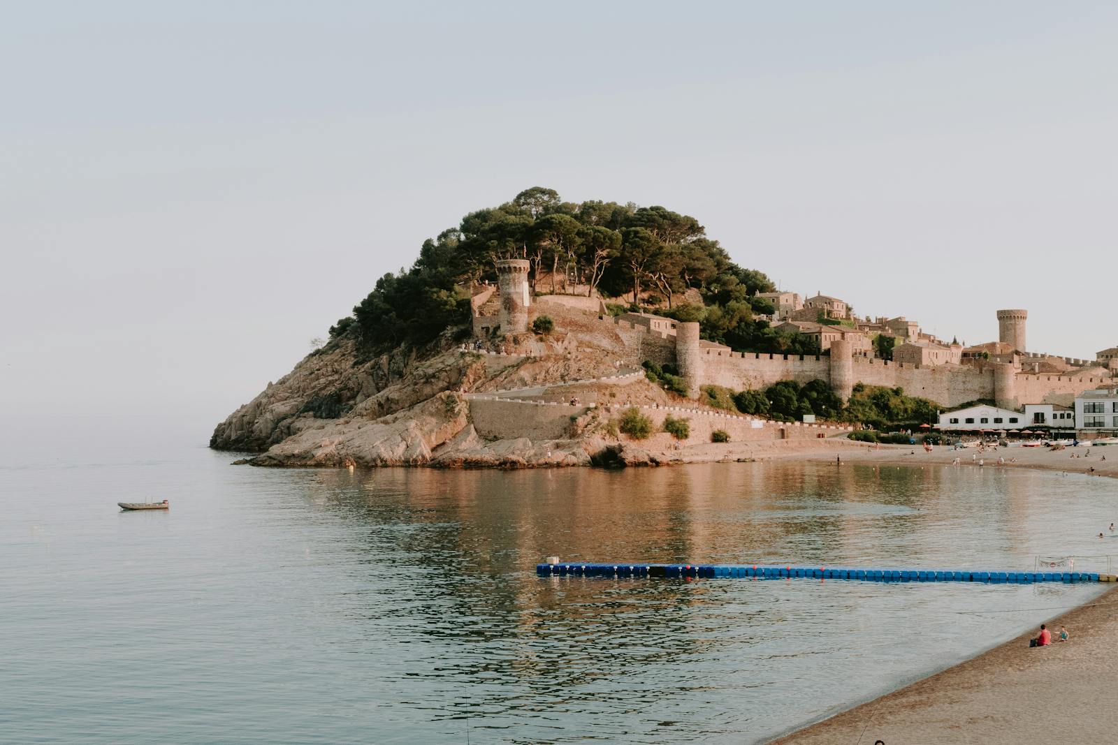 Beautiful view of a medieval castle on the Costa Brava coast with calm sea and sandy beach.