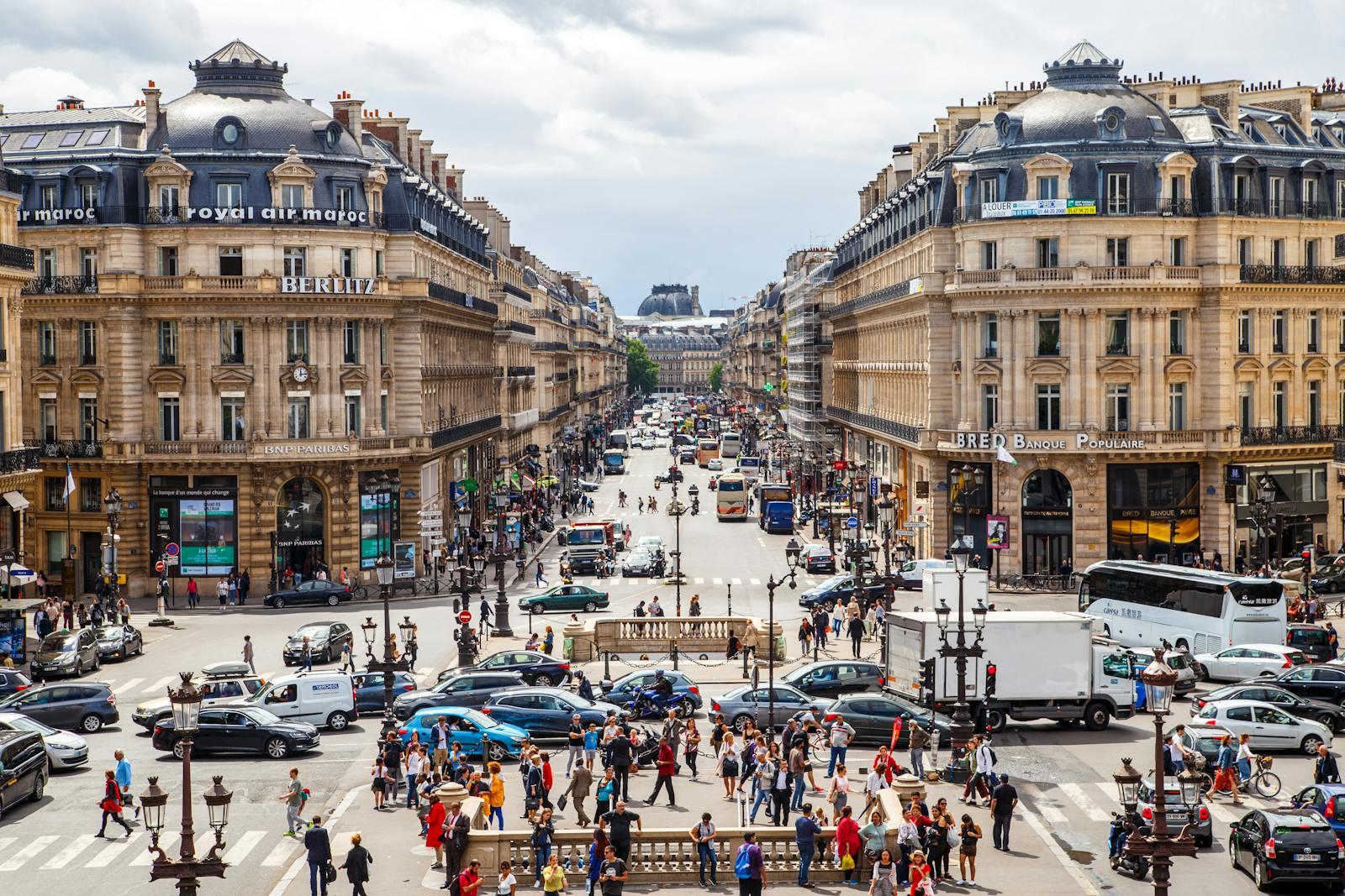 Vibrant street view of central Paris filled with people and traffic on a summer day.