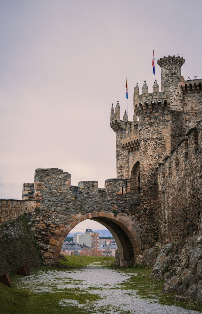 a stone bridge over a river with a castle in the background