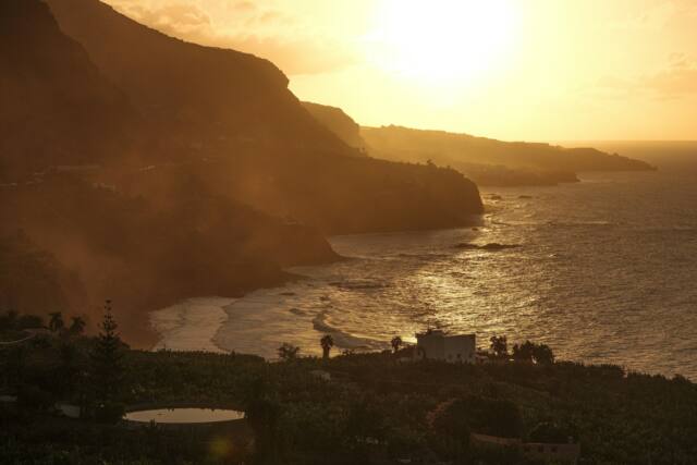 the sun is setting over the ocean and a beach
