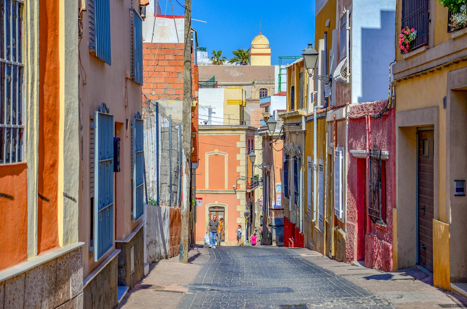 Charming sunlit street in Almería, Spain, with vibrant buildings and architectural charm.
