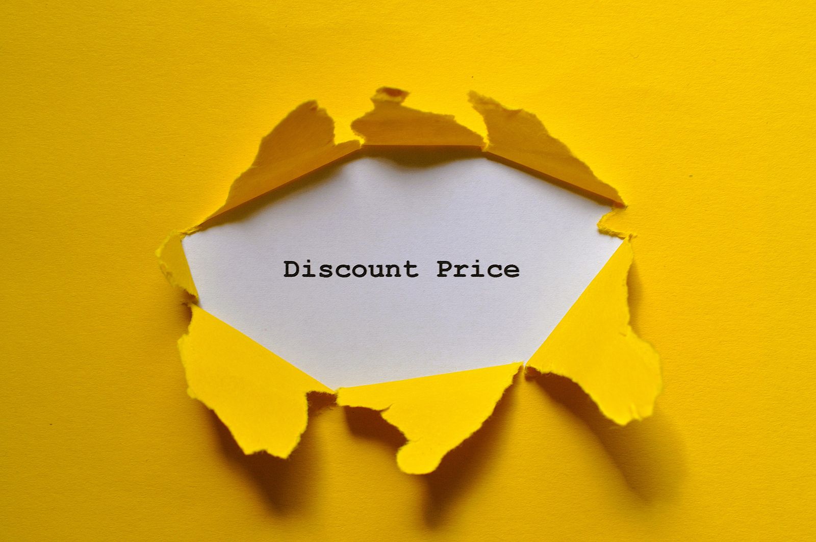 Torn yellow paper revealing 'Discount Price' text, ideal for sales promotions.